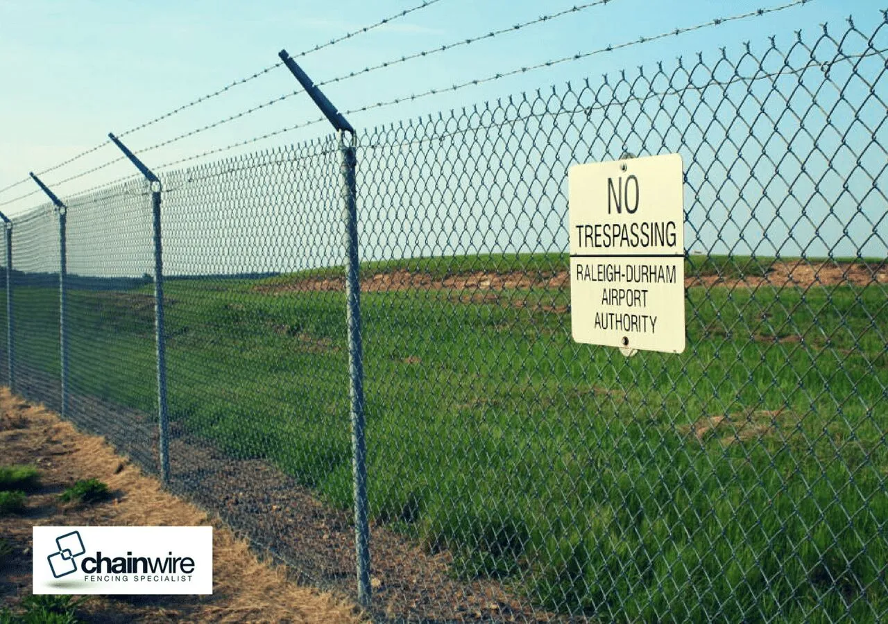 Tall chainwire boundary fence along the edge of a golf course fairway