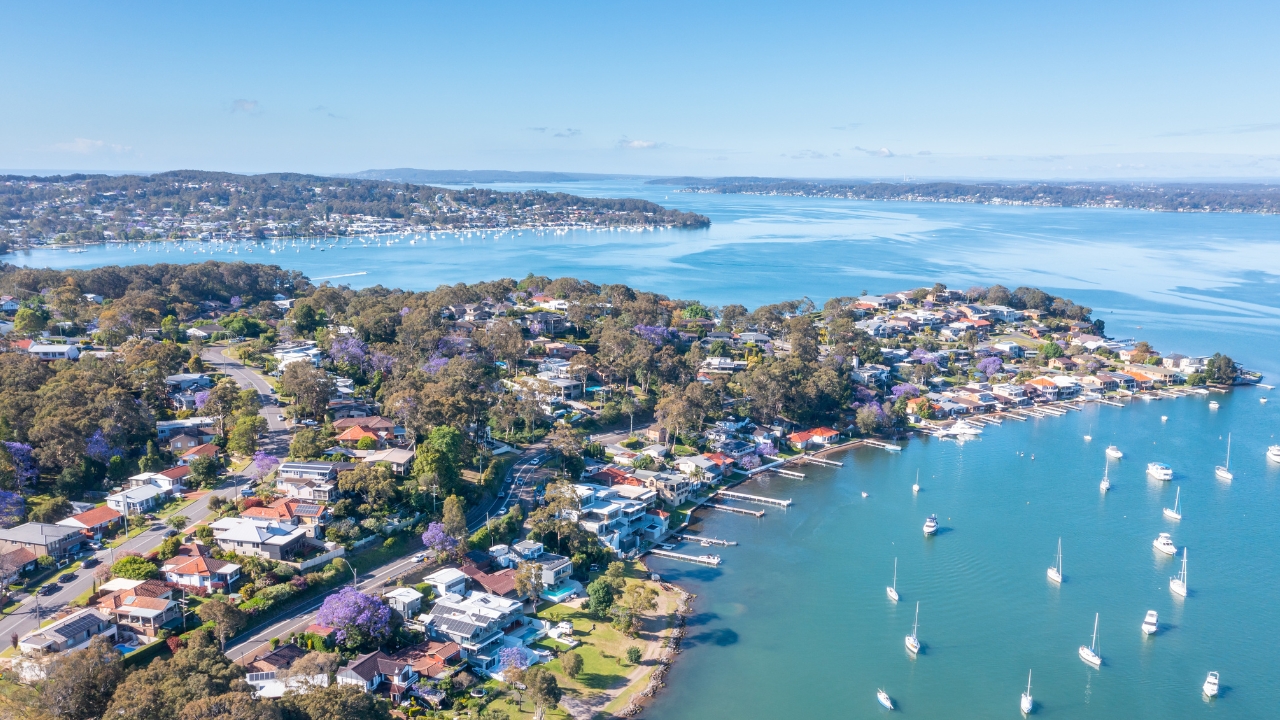 Aerial view of Lake Macquarie shoreline with homes, trees, and moored boats