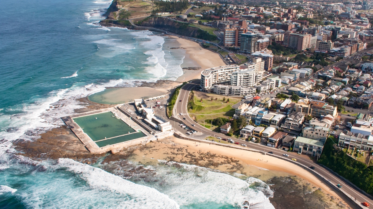 Aerial view of Newcastle coastline with ocean baths and city buildings in view