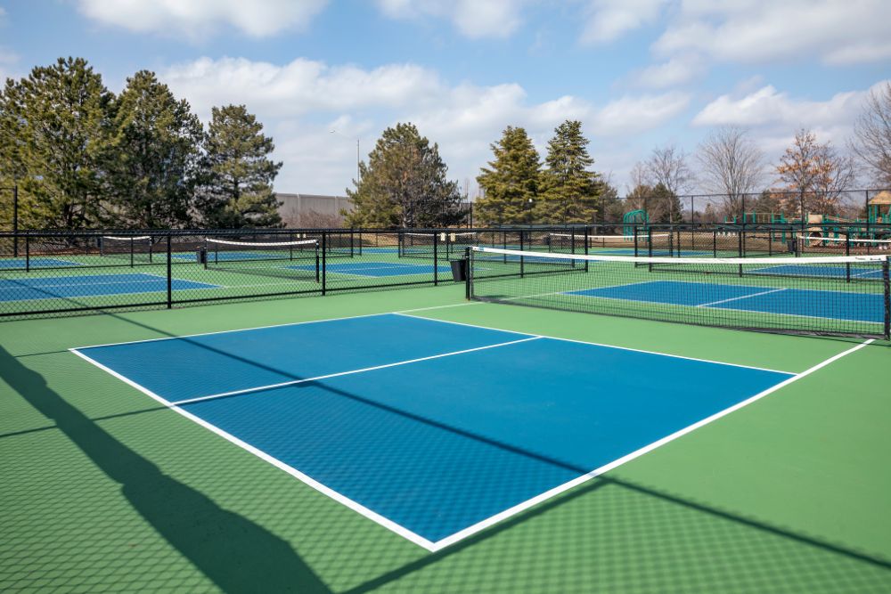 Outdoor pickleball courts with black chain link fencing surrounding each playing area