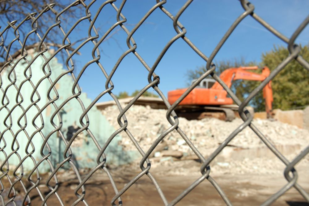 Temporary chainwire fence with excavator at demolition site by Chainwire Fencing Specialist