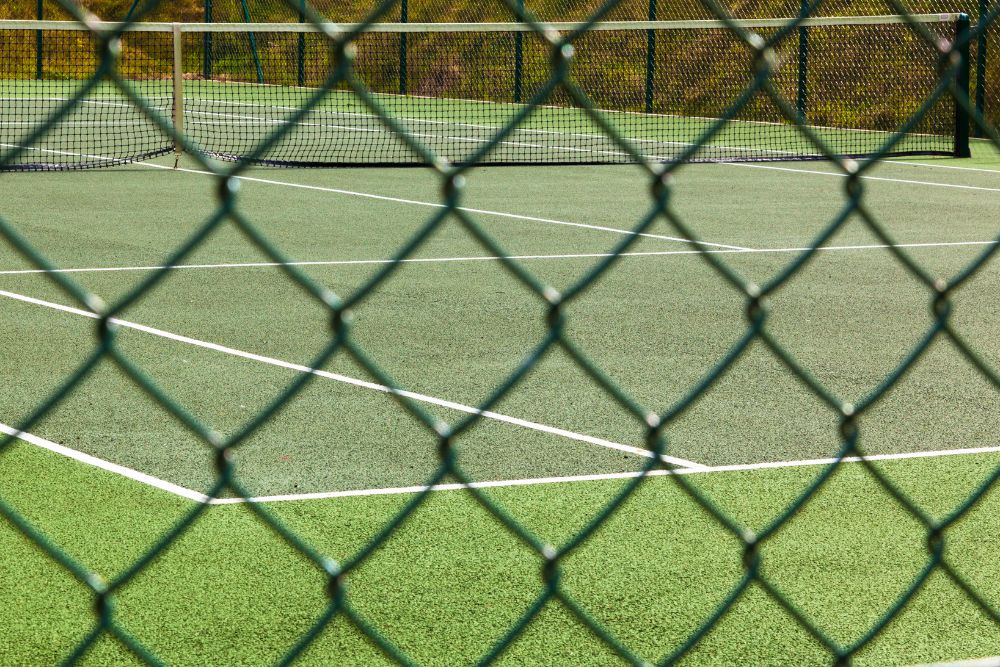 Green game court surrounded by diamond chainwire fencing used for sports enclosures in Newcastle