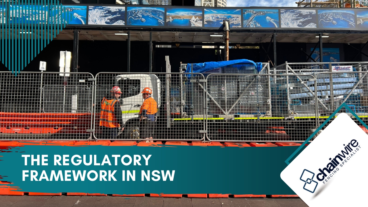 Temporary Fencing Compliance for Construction Sites in NSW - Fencing An urban construction site in NSW featuring two workers in high-visibility vests talking behind a perimeter of temporary metal mesh fencing secured on orange water-filled barriers.